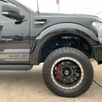 Black Shelby truck with large black and red wheel.