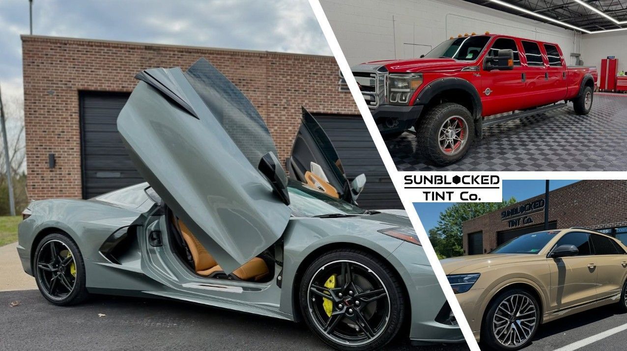 A gray sports car with gull-wing doors open next to a red truck, with an Audi SUV in a partial view.