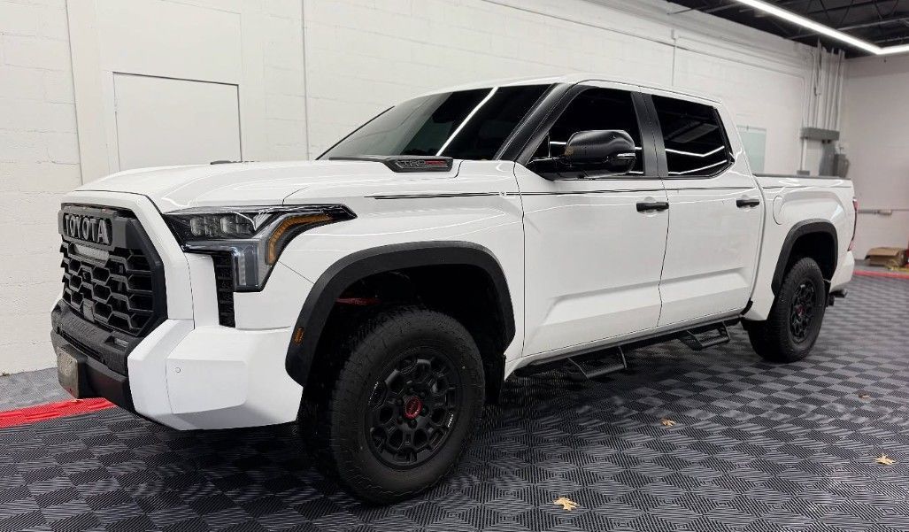 White Toyota Tundra pickup truck with black trim, parked indoors.