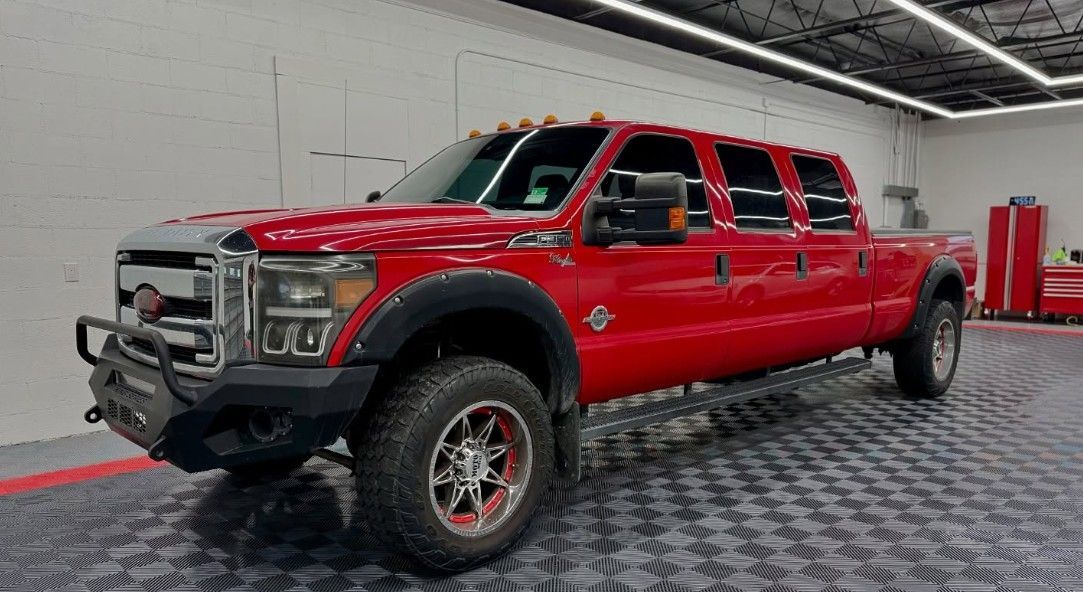 Red extended cab Ford truck with off-road tires, parked in a garage.