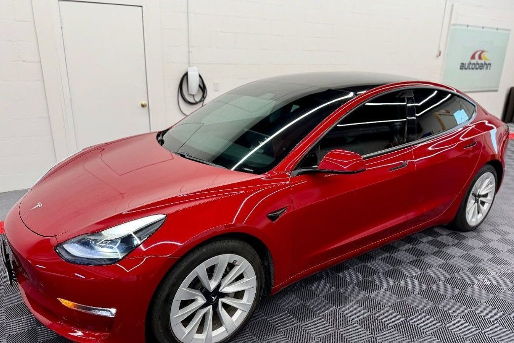 Red Tesla Model 3 car parked indoors.