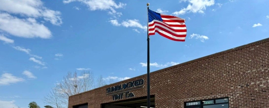American flag waving in the wind in front of a brick building on a sunny day.
