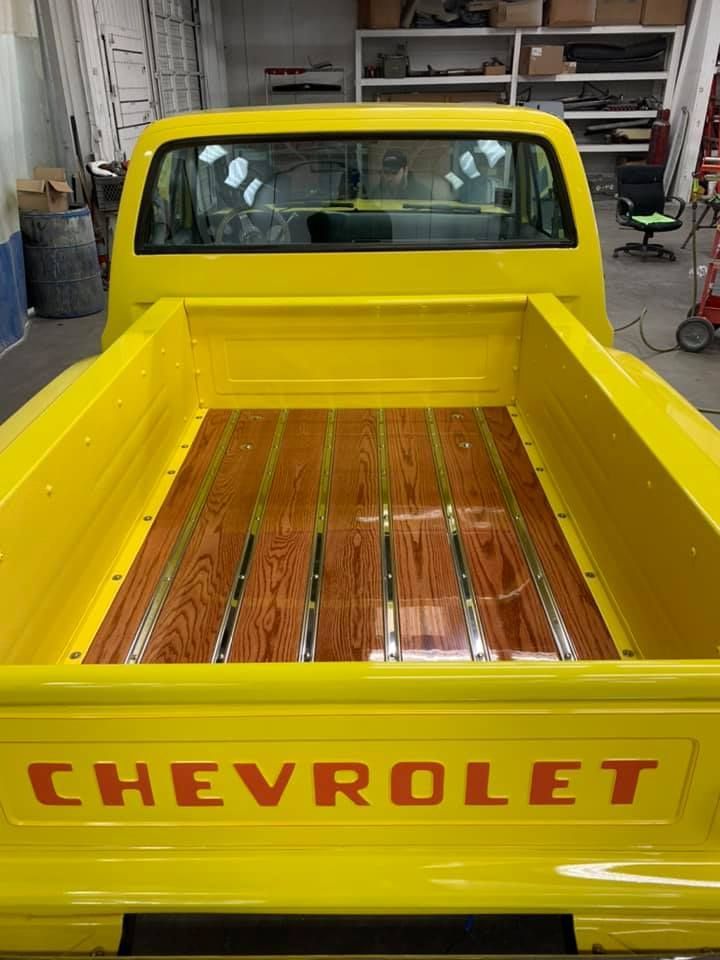Yellow Chevrolet pickup truck bed with wooden slats and chrome strips.