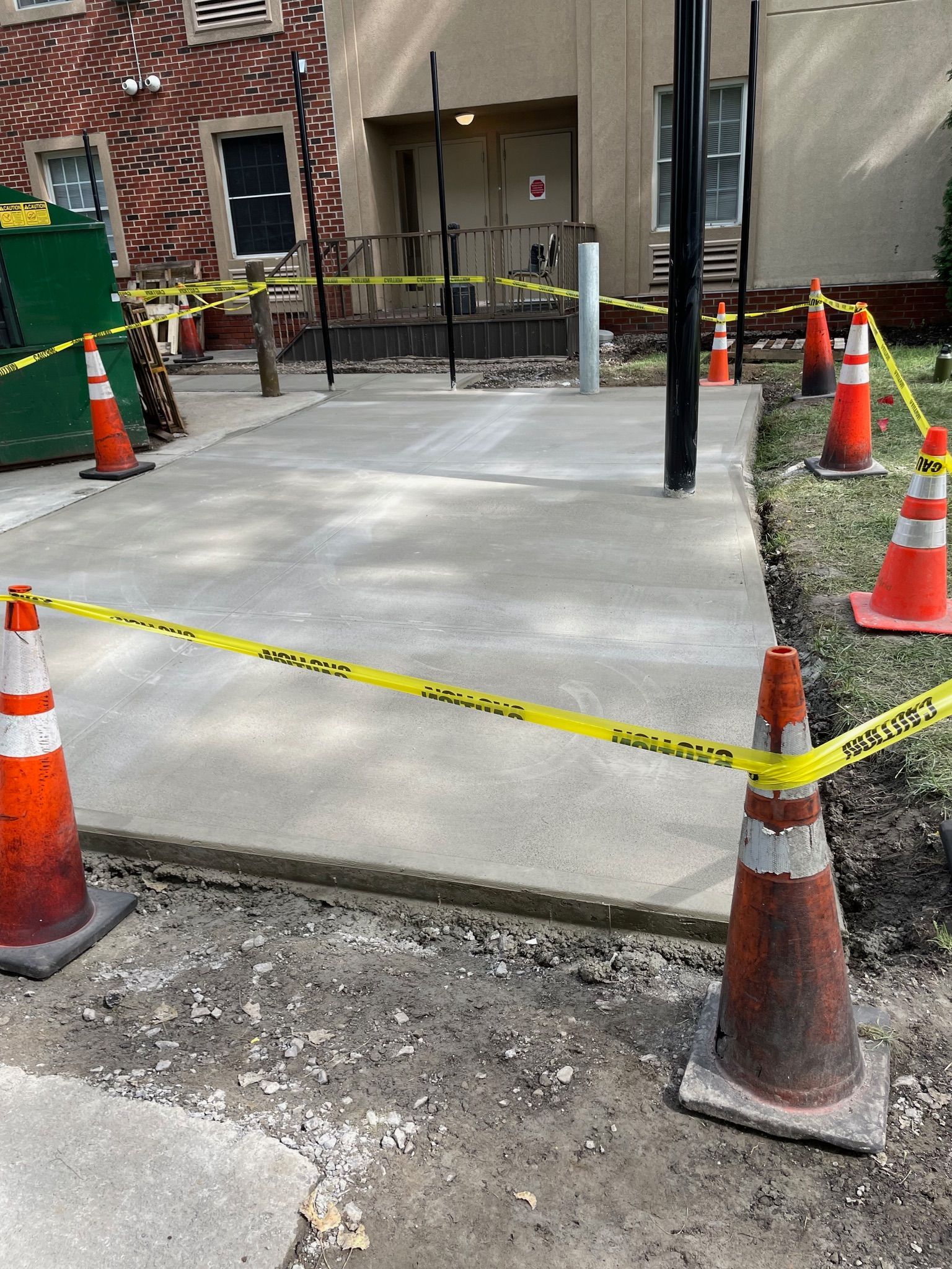 A concrete walkway is being built next to a brick building.