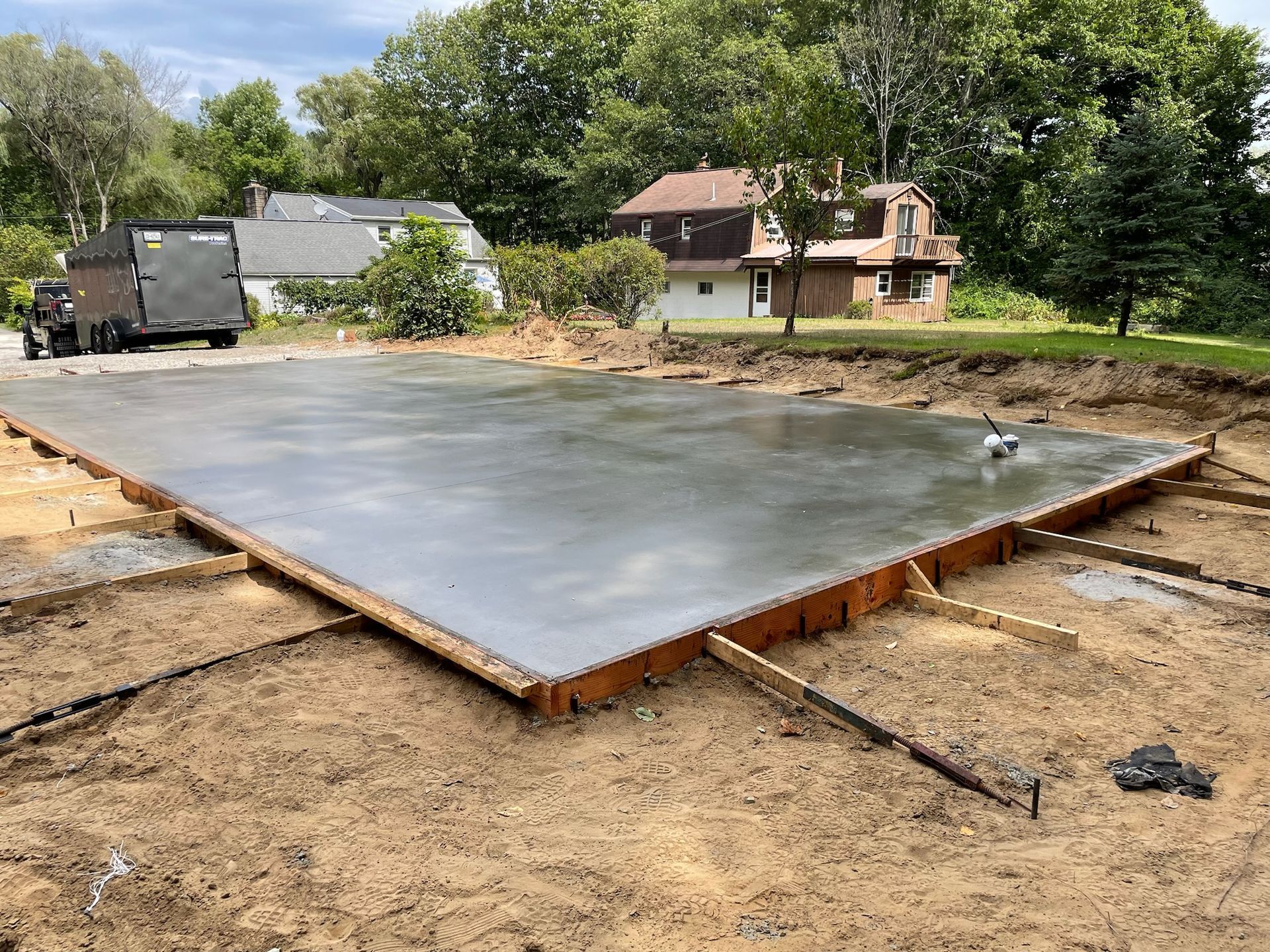 A large concrete slab is sitting on top of a dirt field in front of a house.