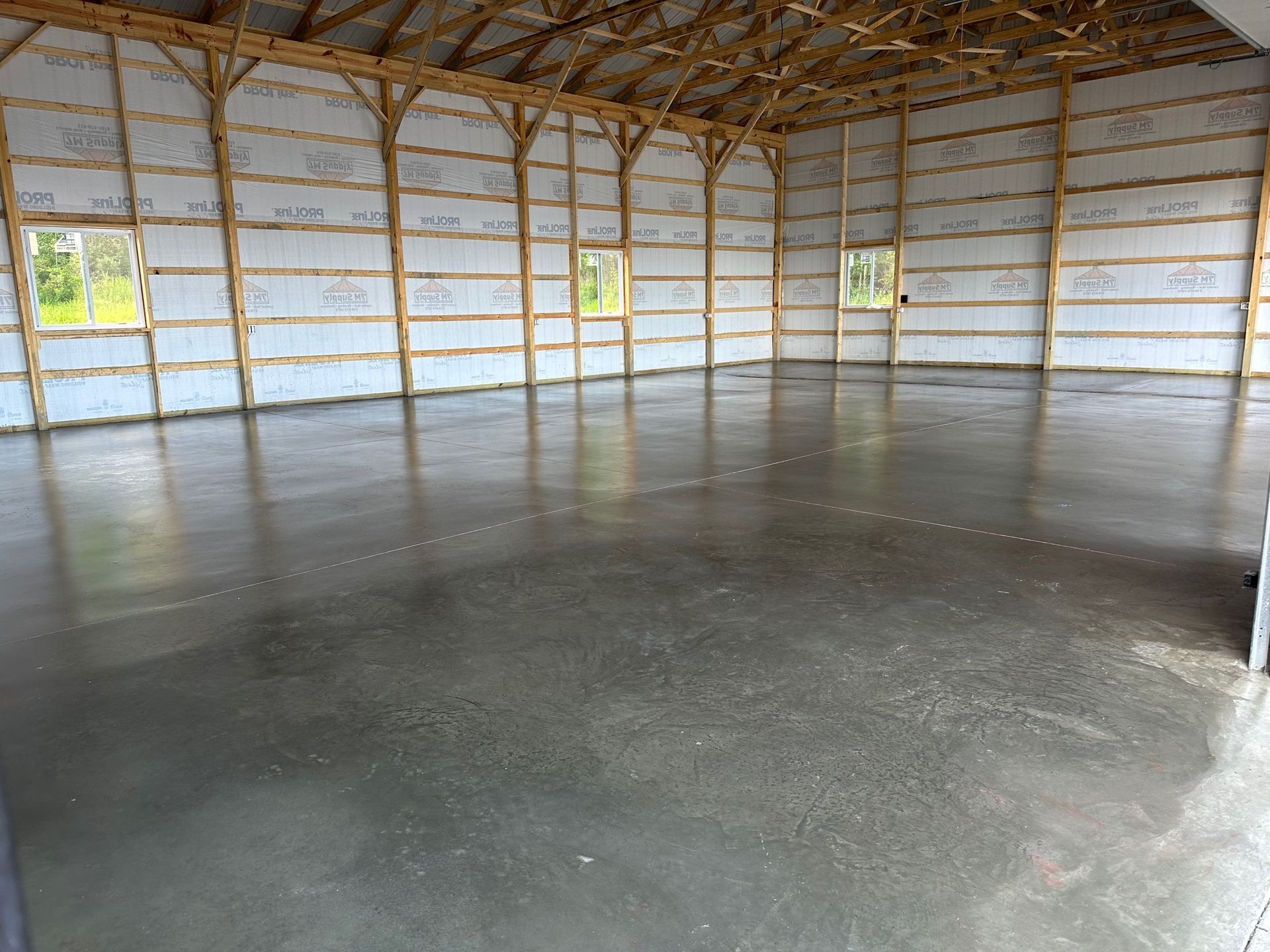 A large empty building with a concrete floor and wooden walls.
