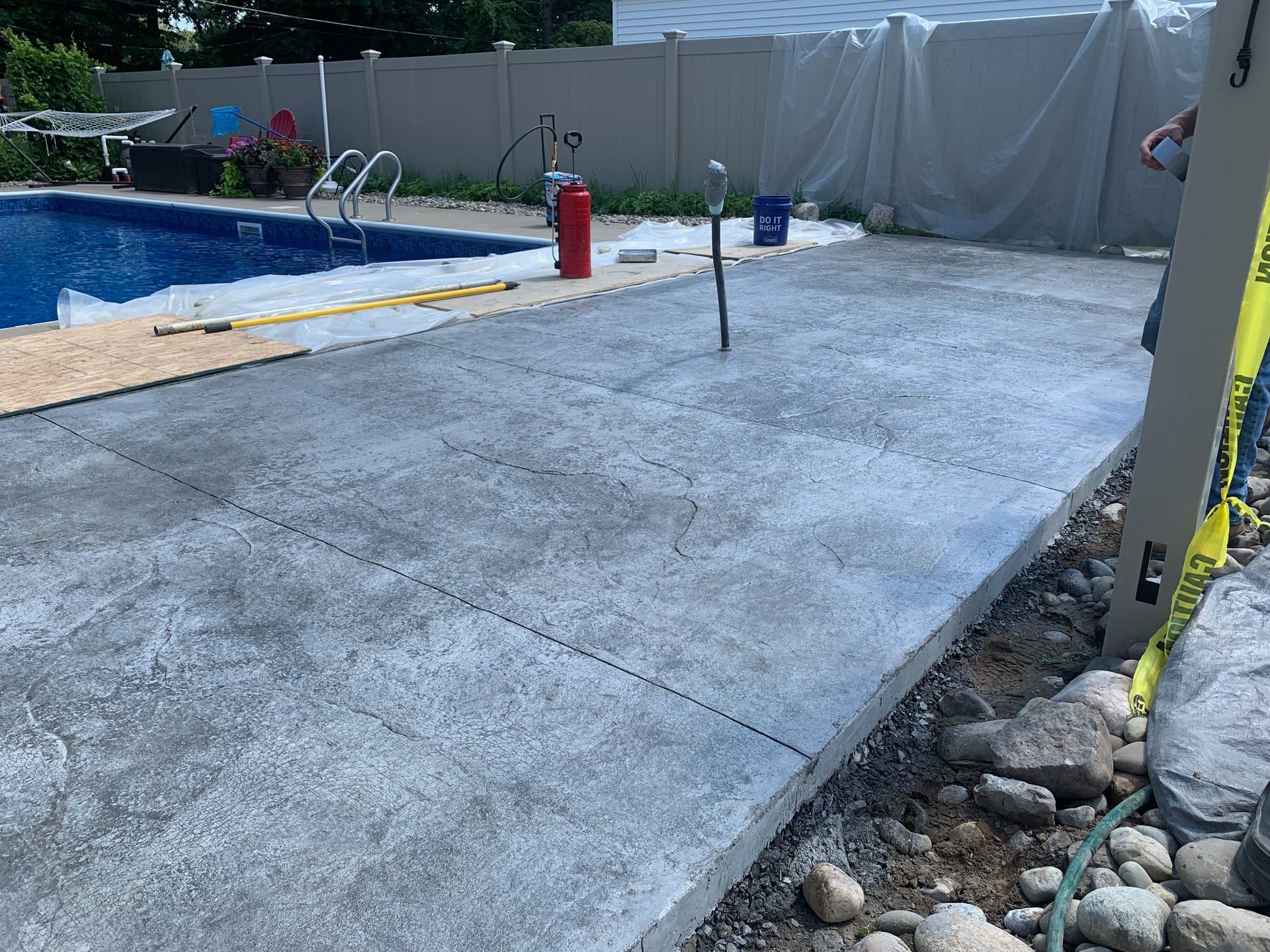 A concrete patio is being built next to a swimming pool.