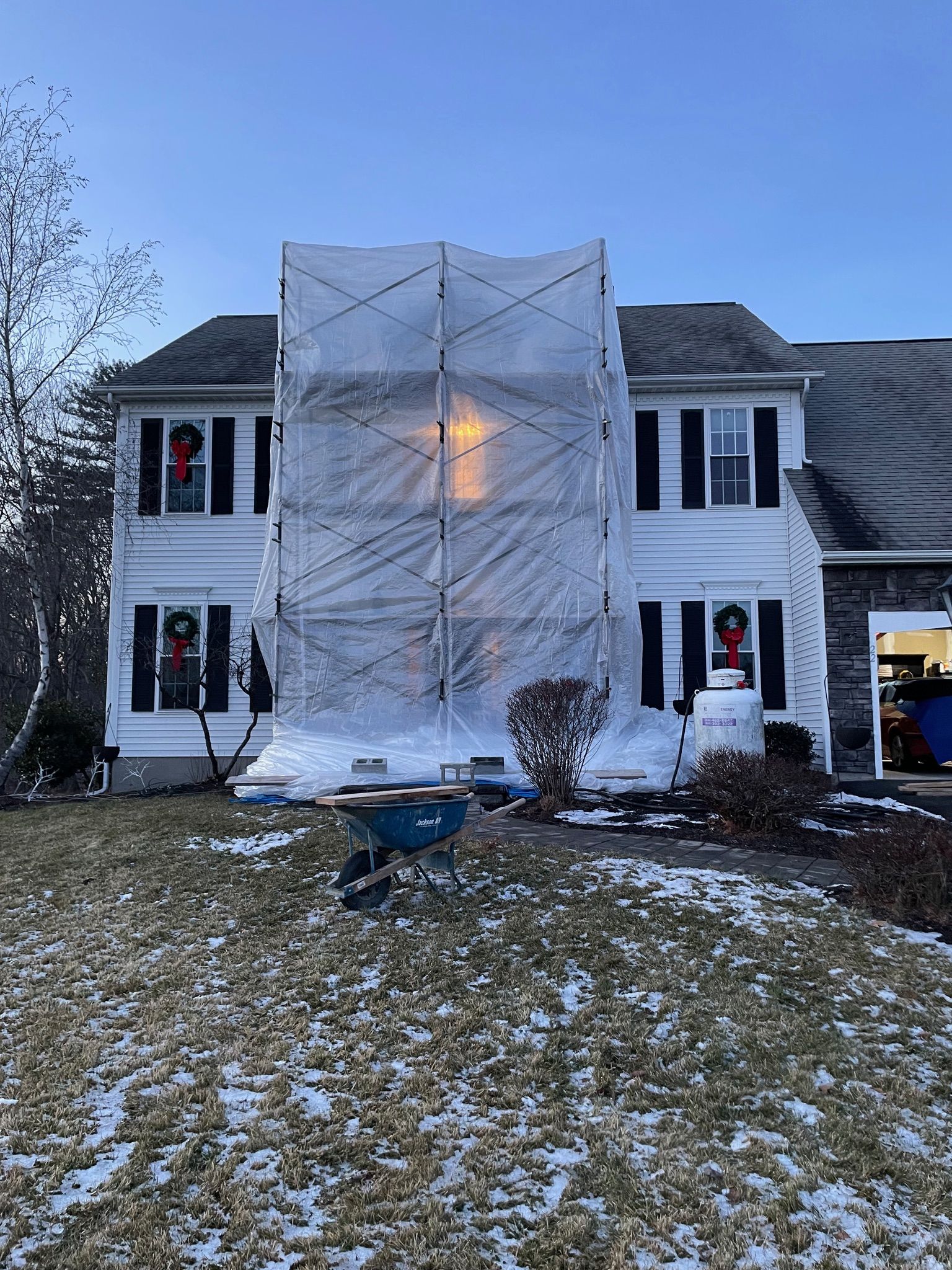 A house is covered in plastic while being painted.