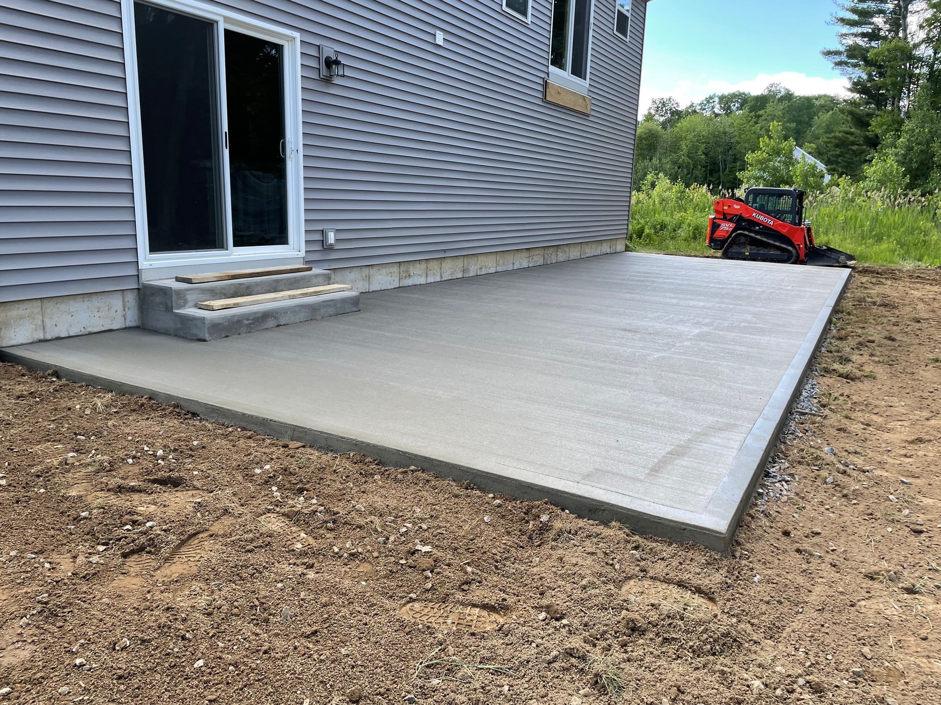 A concrete patio is being built in front of a house.