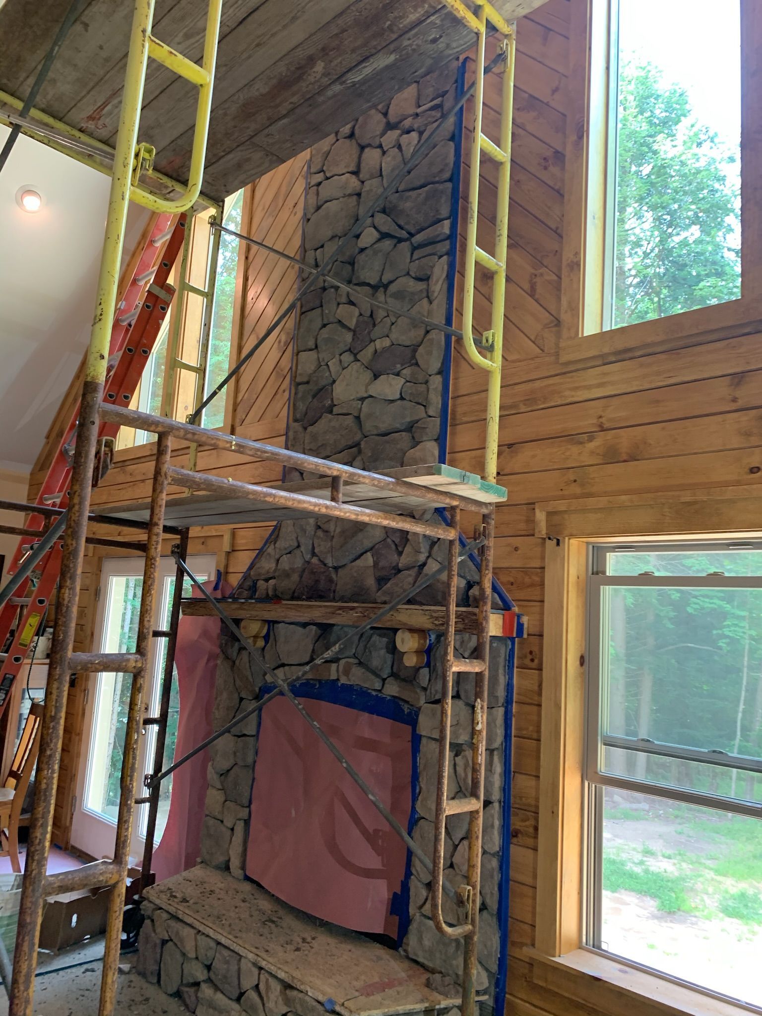 A stone fireplace is being built in a wooden house.