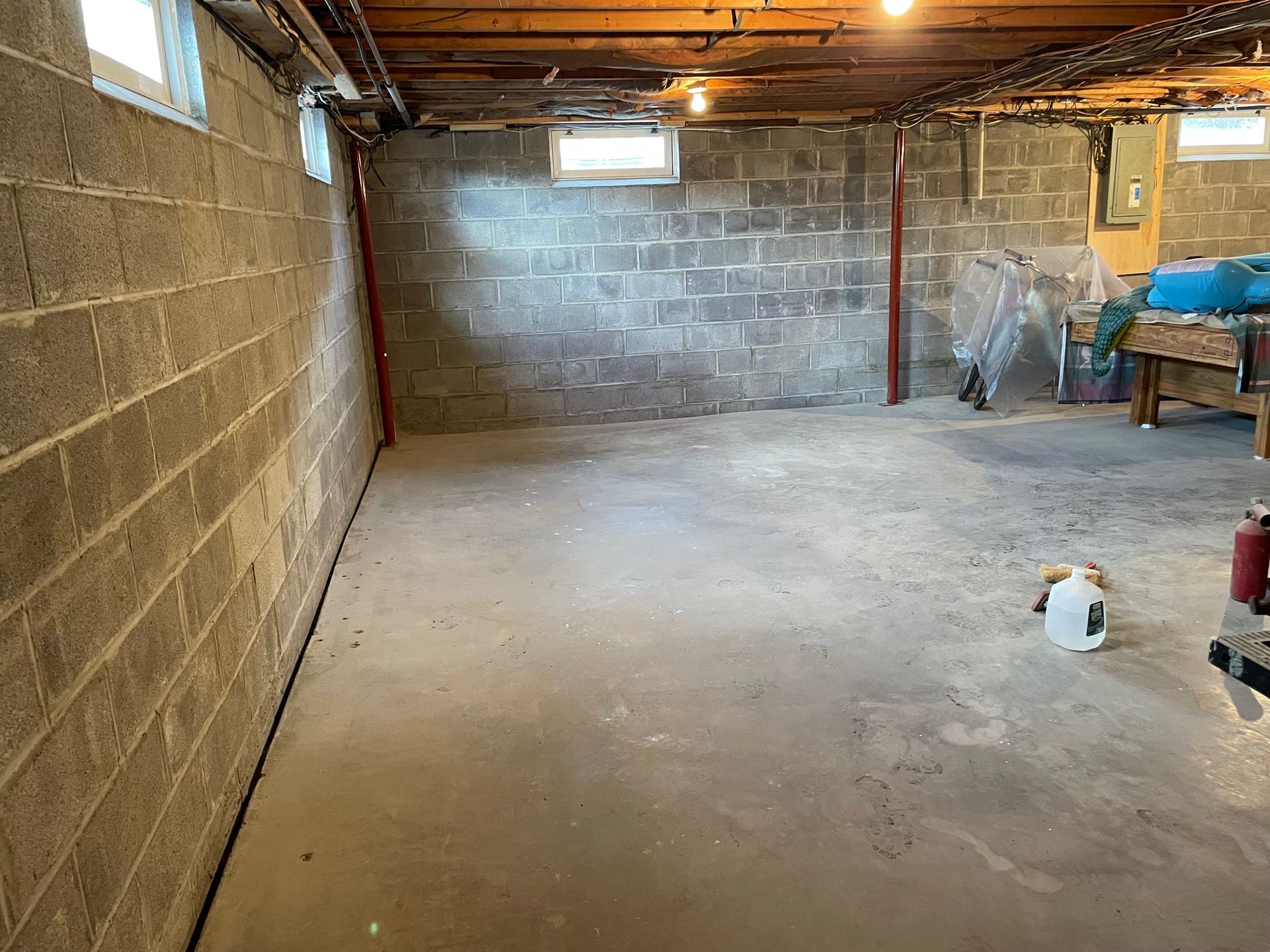 An empty basement with brick walls and a concrete floor.