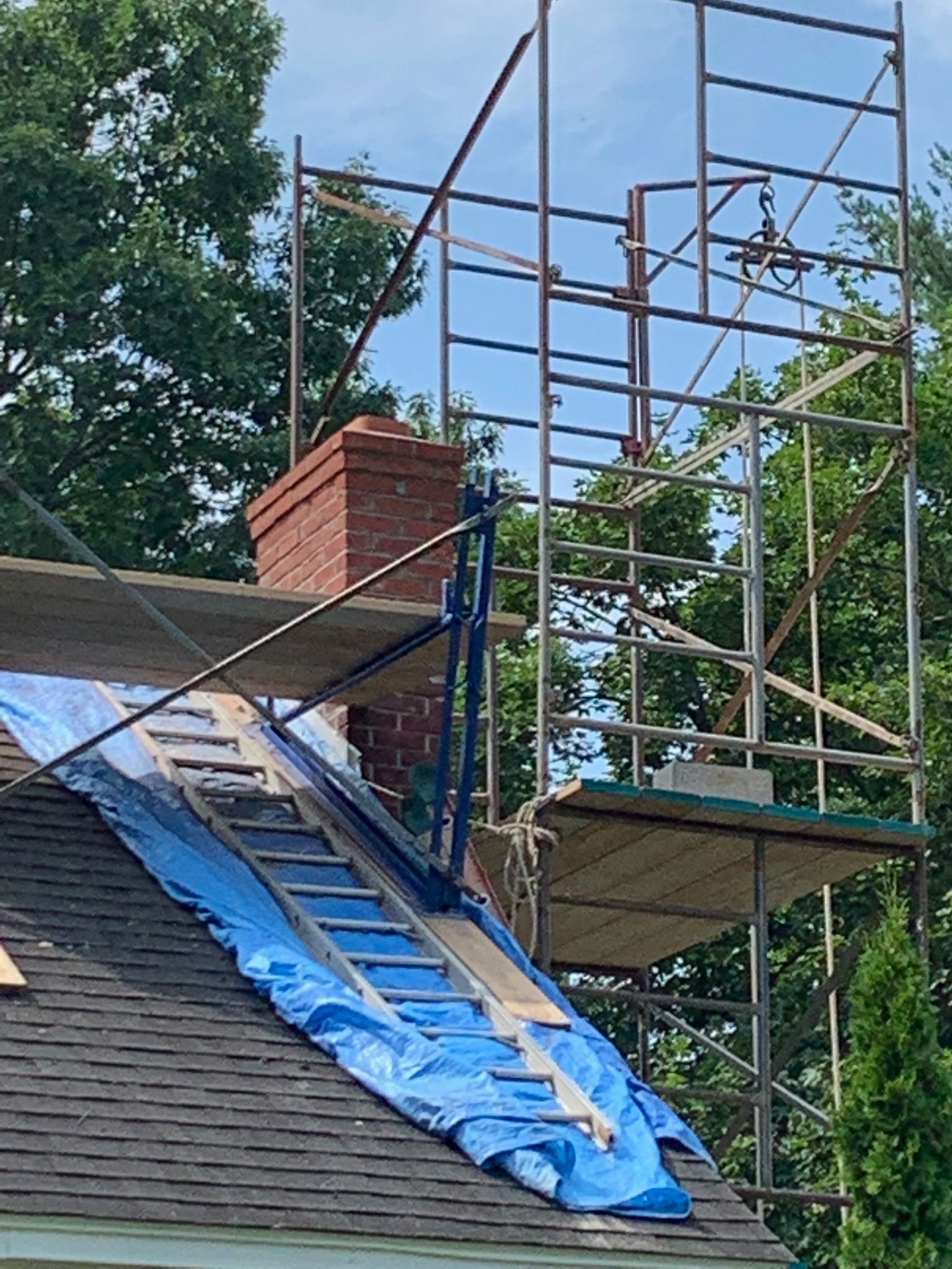 A ladder is sitting on top of a roof next to a scaffolding.