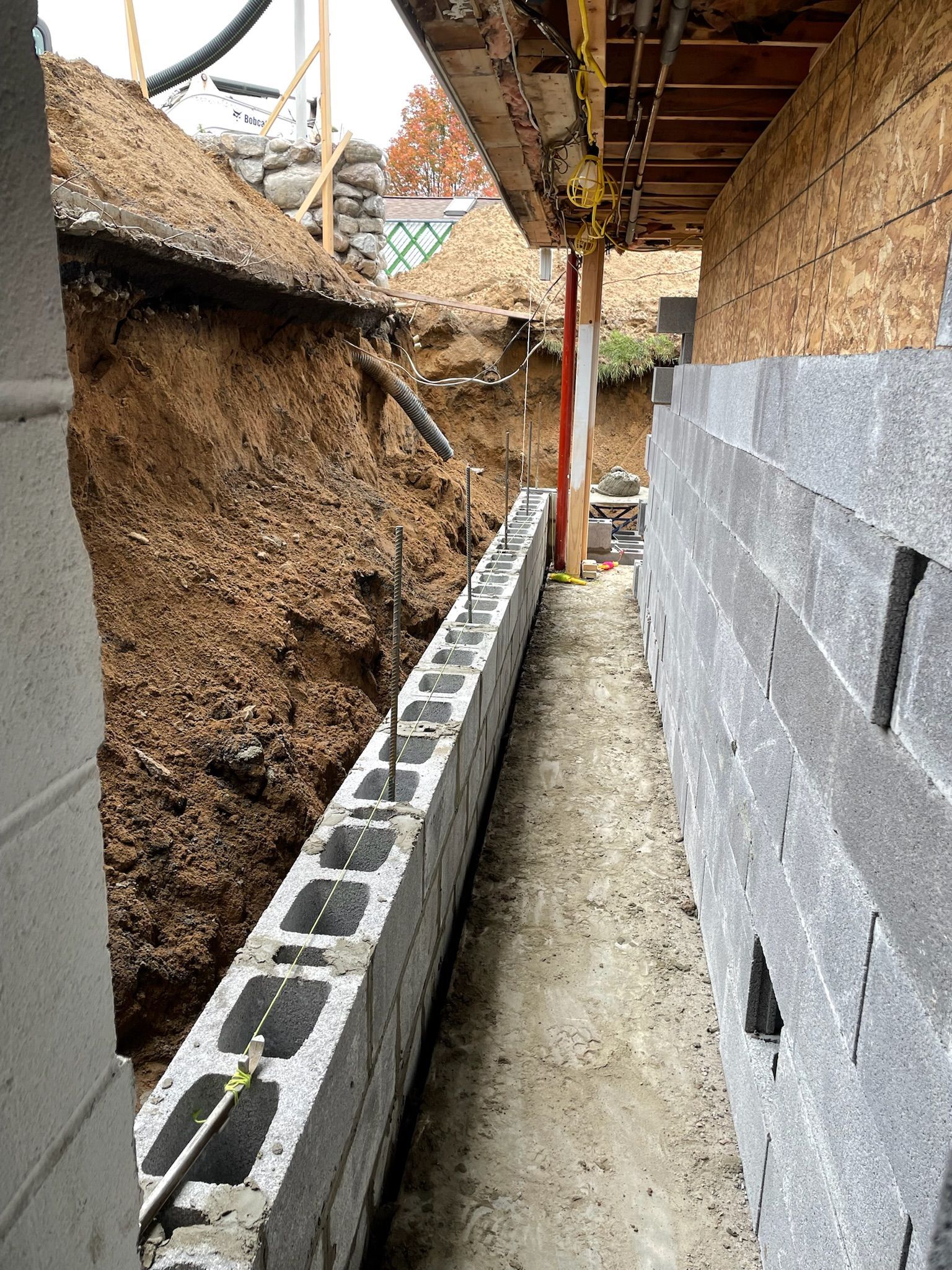 A brick wall is being built next to a hole in the ground.