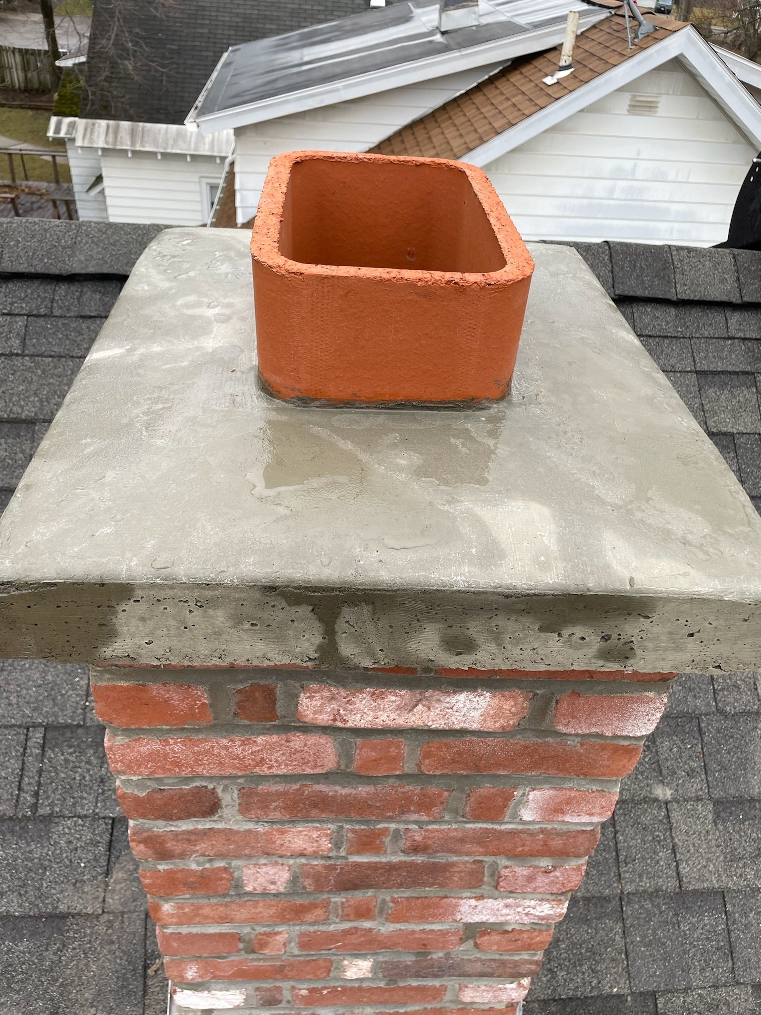 A brick chimney is sitting on top of a roof.