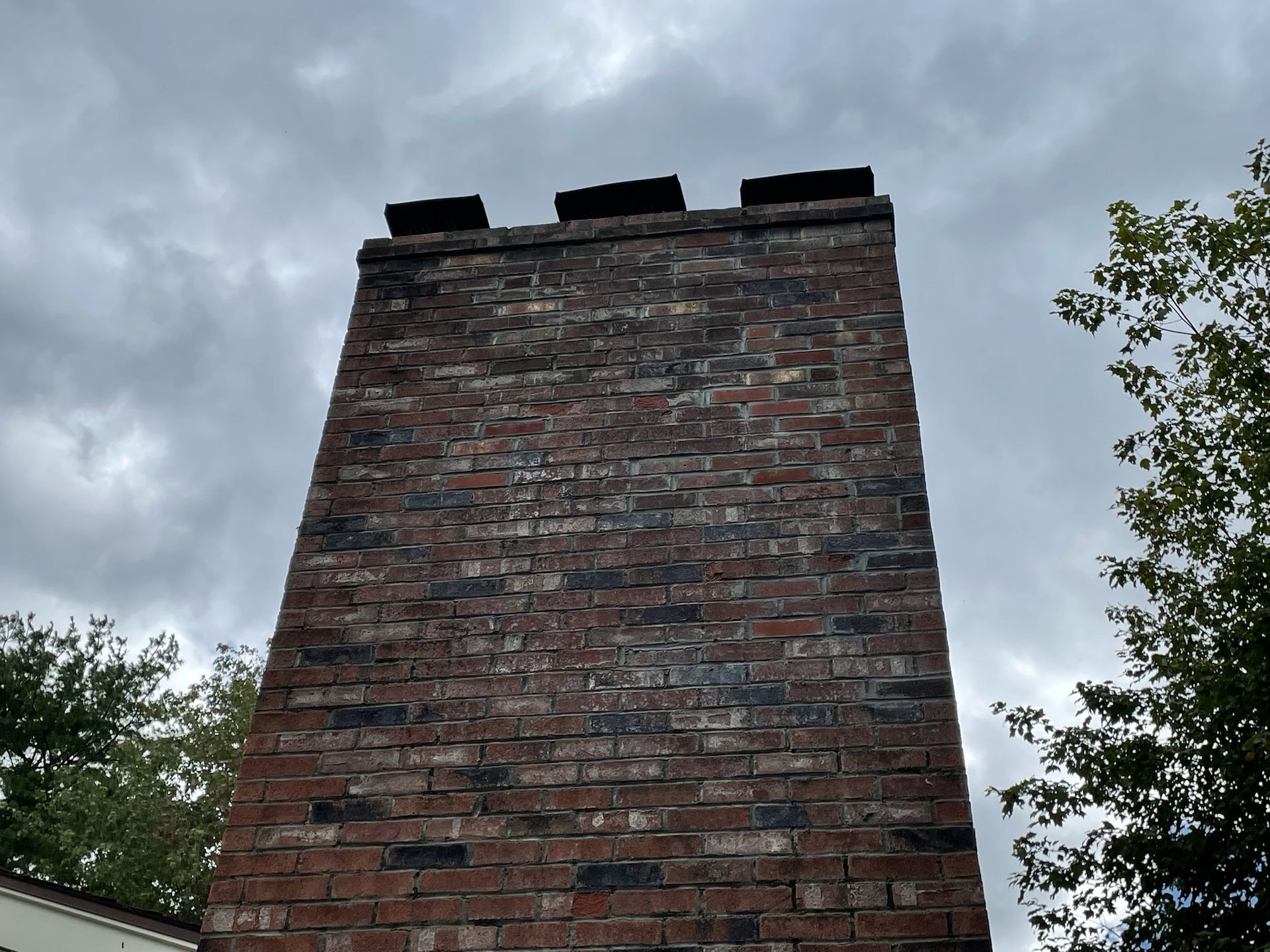 A brick chimney with a cloudy sky in the background
