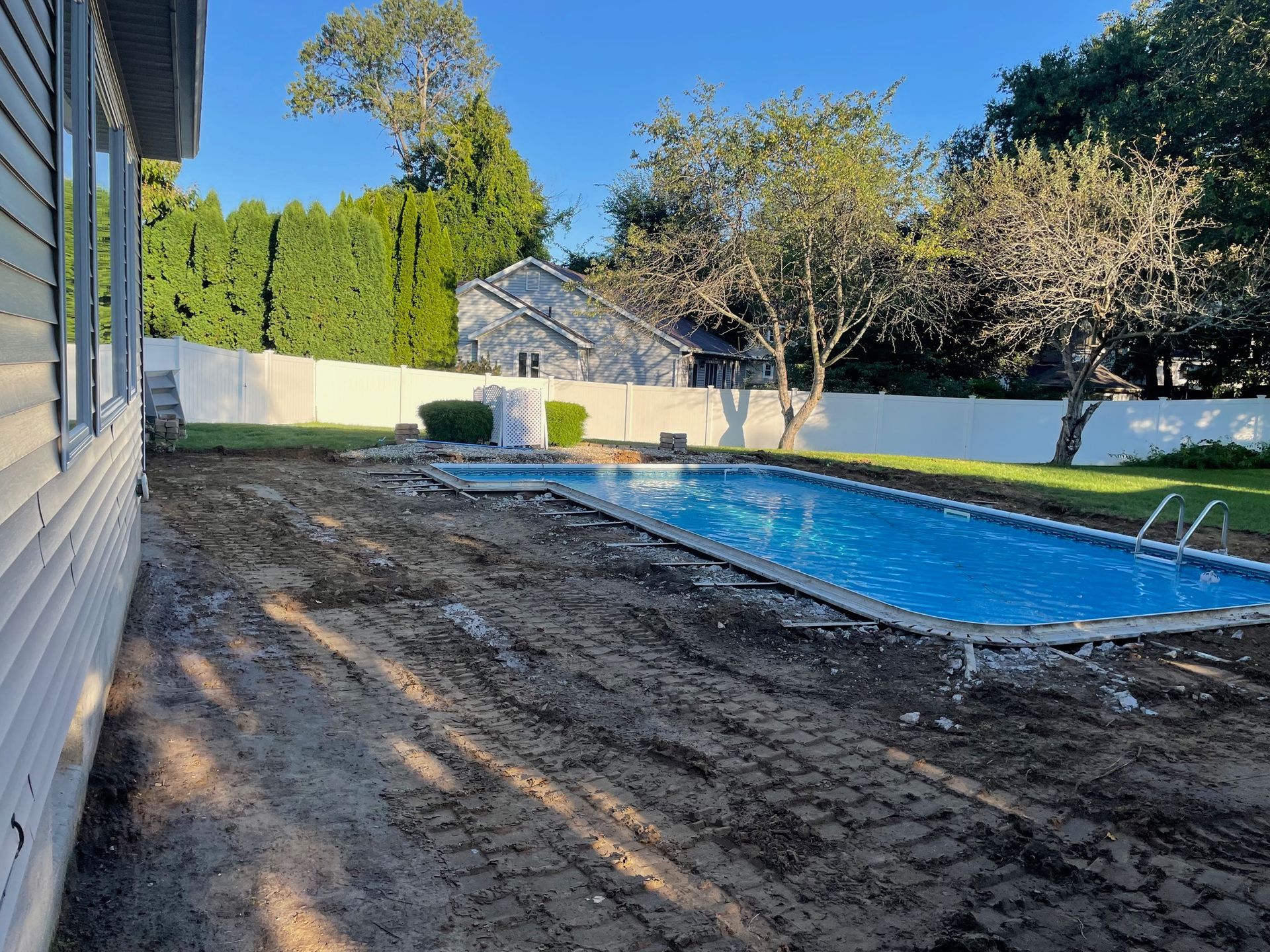 A large swimming pool is in the backyard of a house.