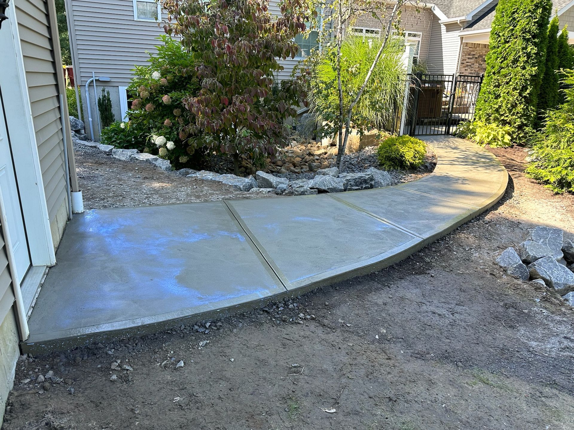 A concrete walkway is being built in the backyard of a house