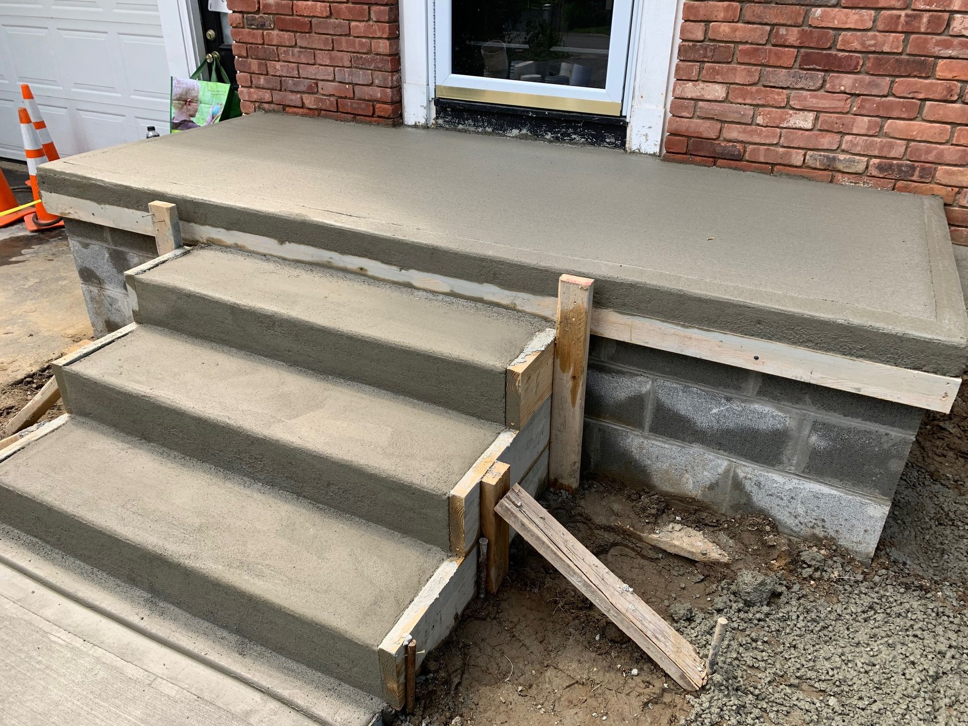 A concrete porch is being built in front of a brick house