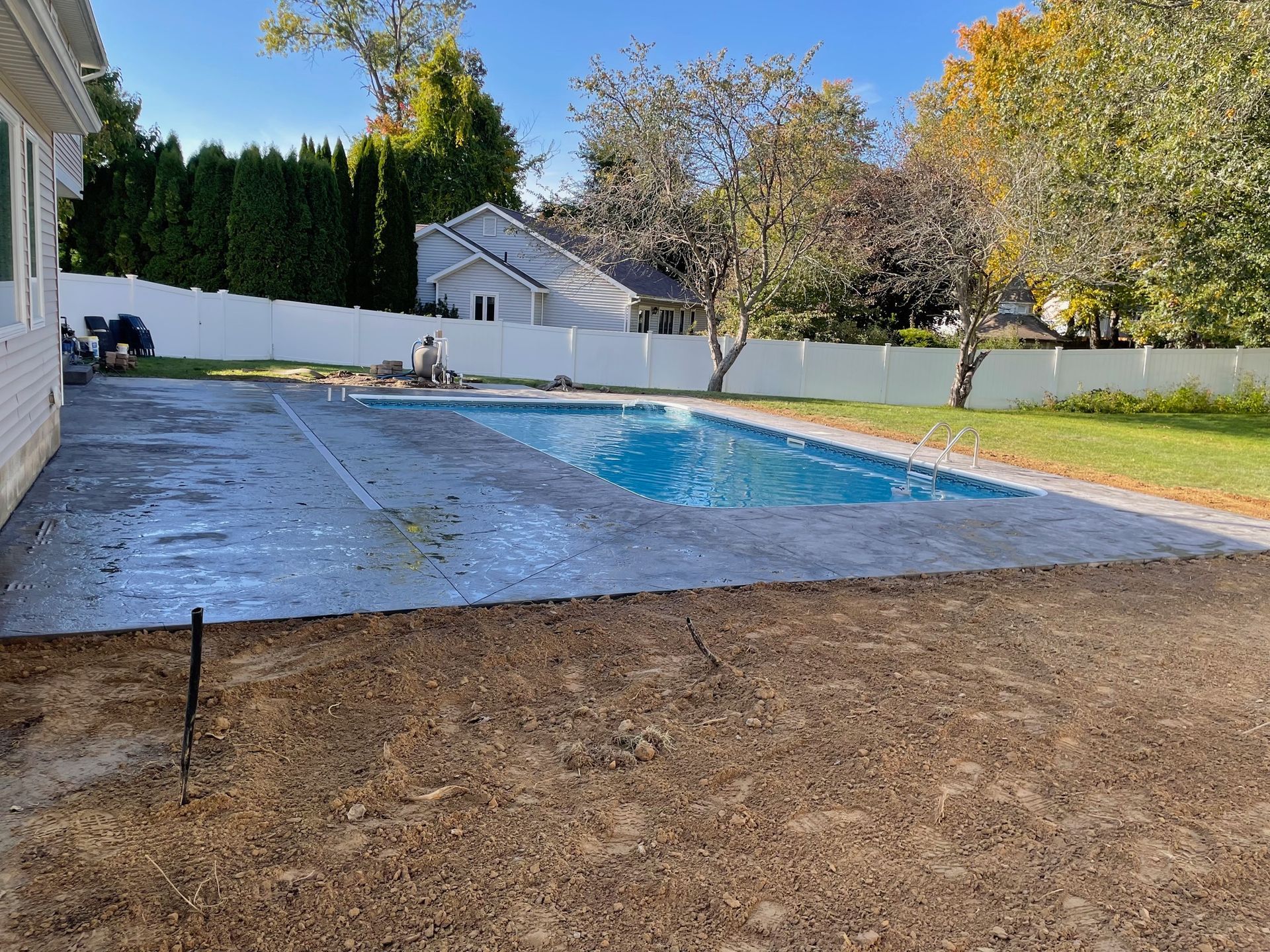 A large swimming pool is in the backyard of a house