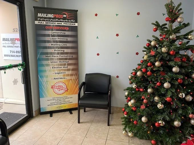 Interior shot of an office entrance with a Christmas tree, a black chair, and a banner for Mailing Pros.