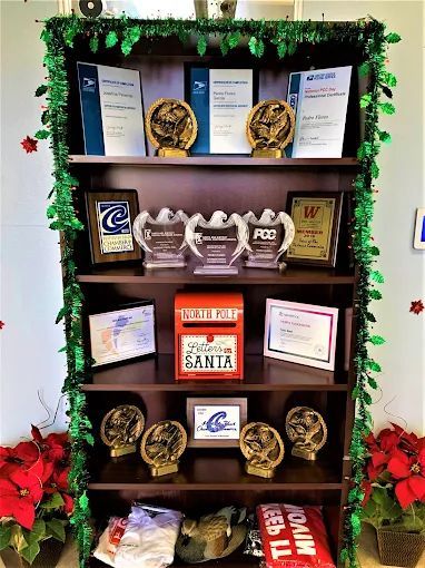 A bookshelf decorated with green garland and poinsettias, holding awards, a 