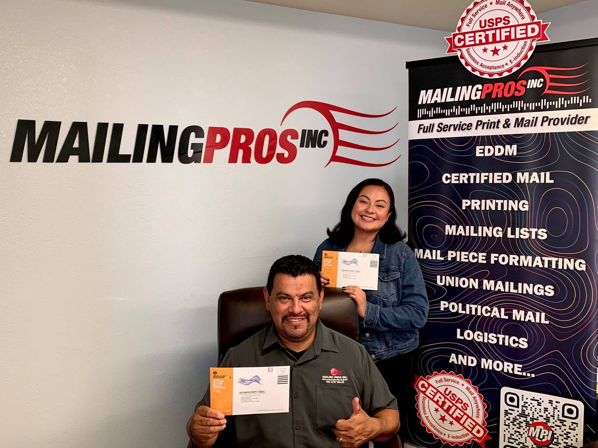 Two people holding mail in front of a company logo and services sign.