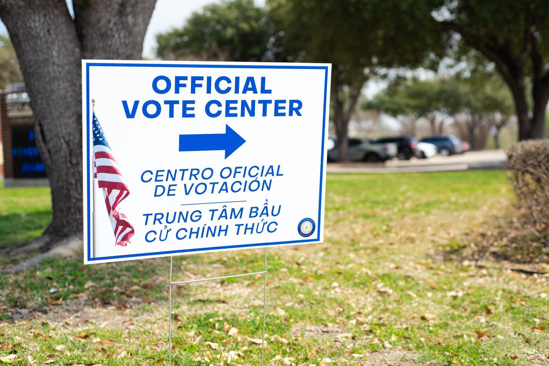 Official Vote Center sign with translations and an American flag points right.