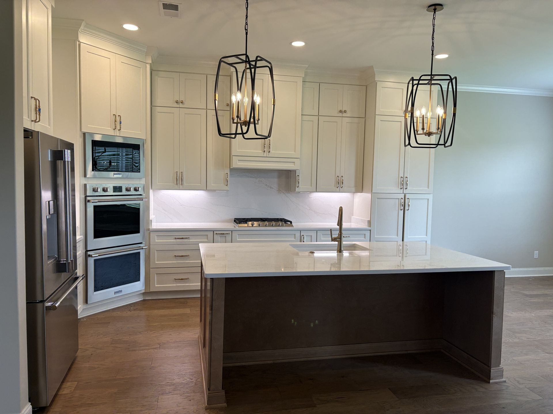 Bright modern kitchen with white cabinets, stainless appliances, and a large island with pendant lights
