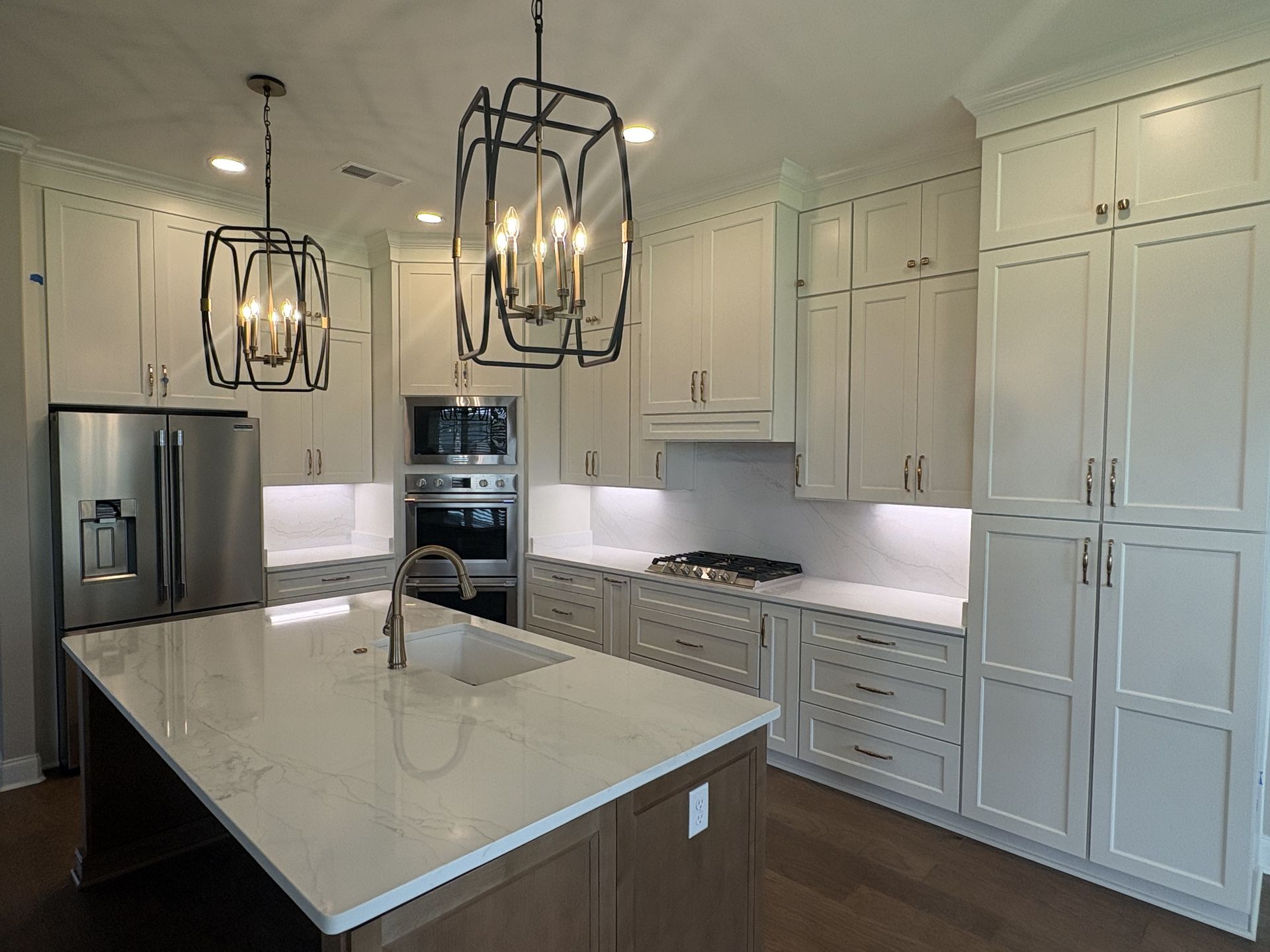 Bright modern kitchen with white cabinets, stainless appliances, and a large marble island under pendant lights