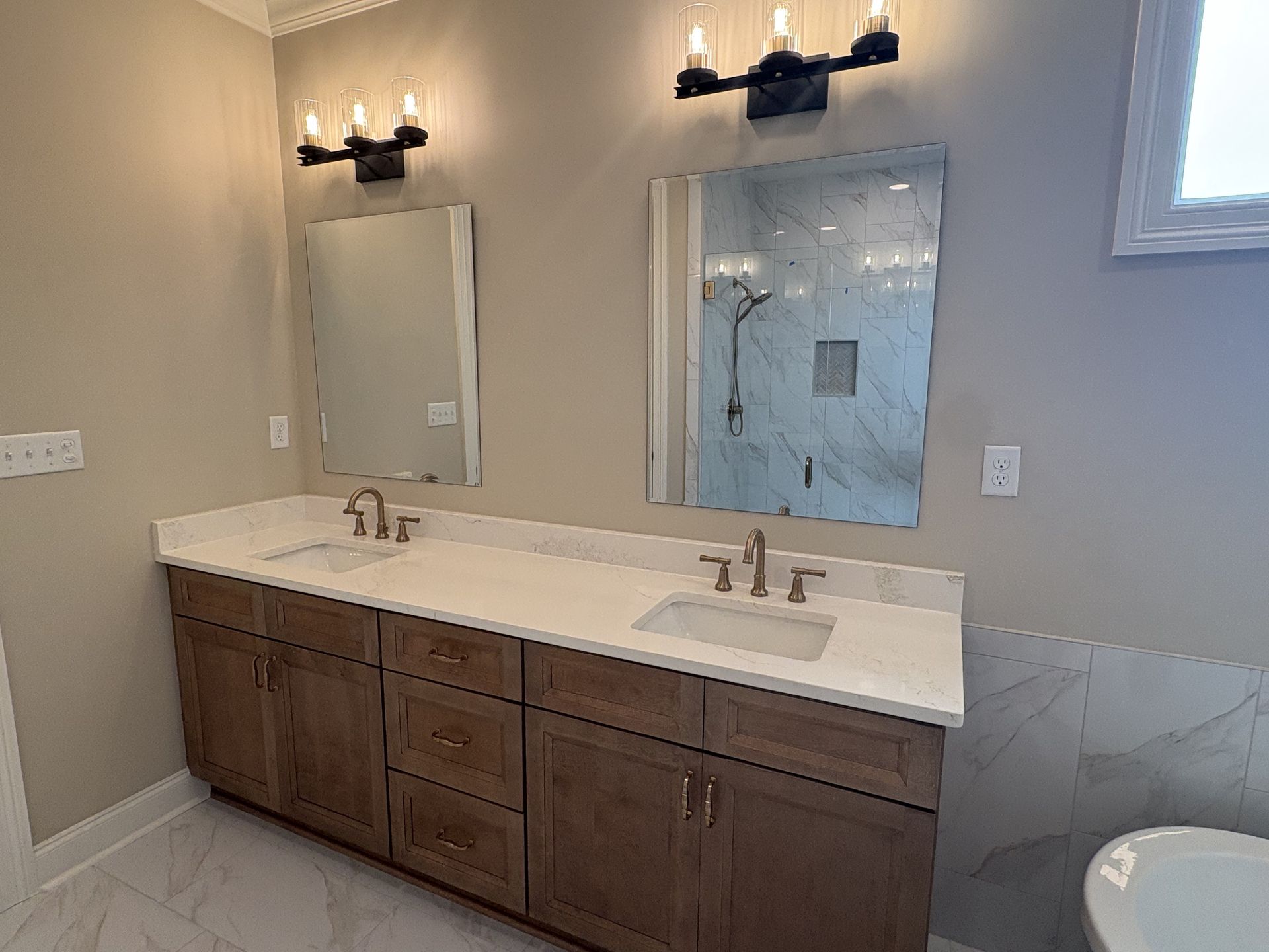 Modern bathroom with double vanity, large mirror, wall sconces, and neutral gray walls.