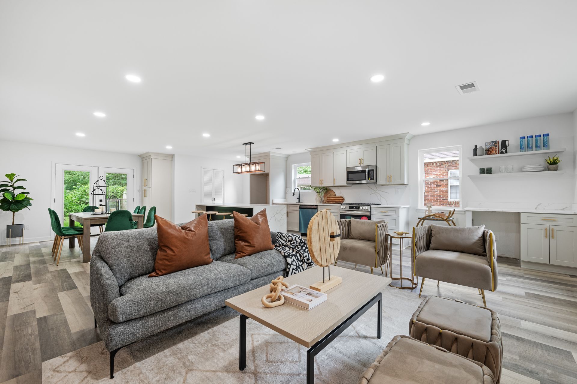 Modern open-concept living space with gray sofa, kitchen, dining area, and neutral color scheme.
