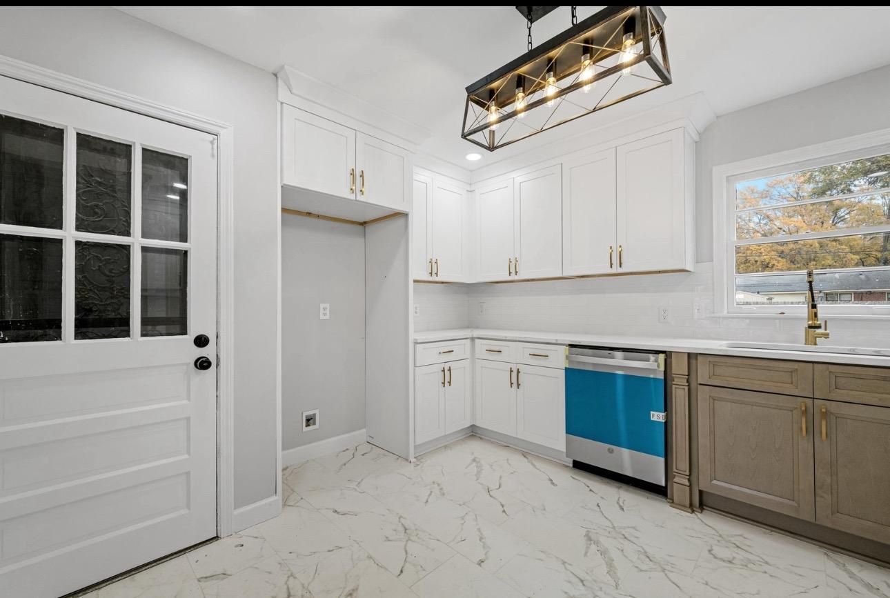 Kitchen with white cabinets, blue dishwasher, and marble-look tile flooring.