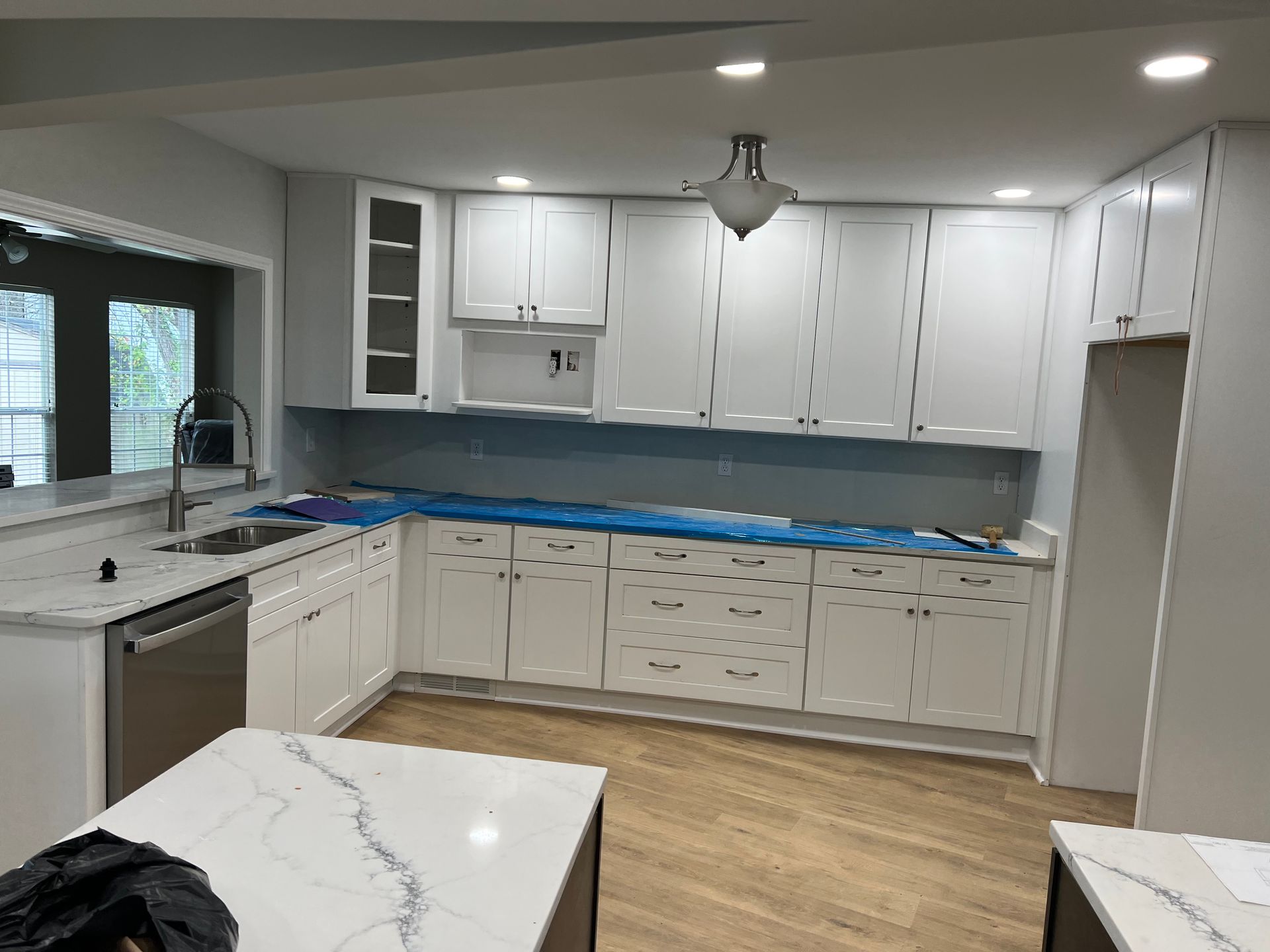 White kitchen cabinets with light countertops and a large window.