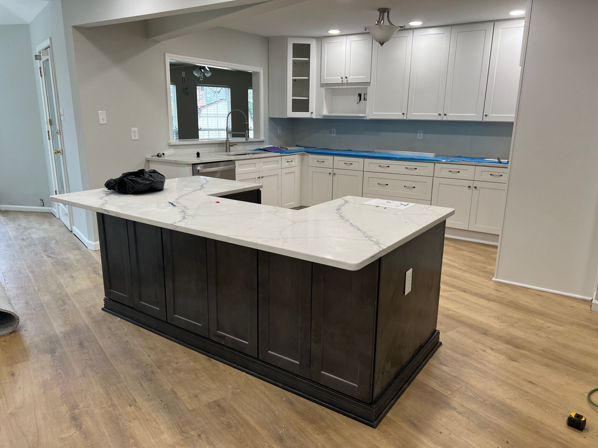 Newly renovated kitchen with dark brown island, white countertops, and white cabinets.