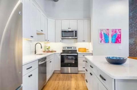 White kitchen with stainless steel appliances, white cabinets, and island with a blue bowl.