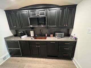 Black kitchen cabinets with a granite countertop, sink, and appliances.