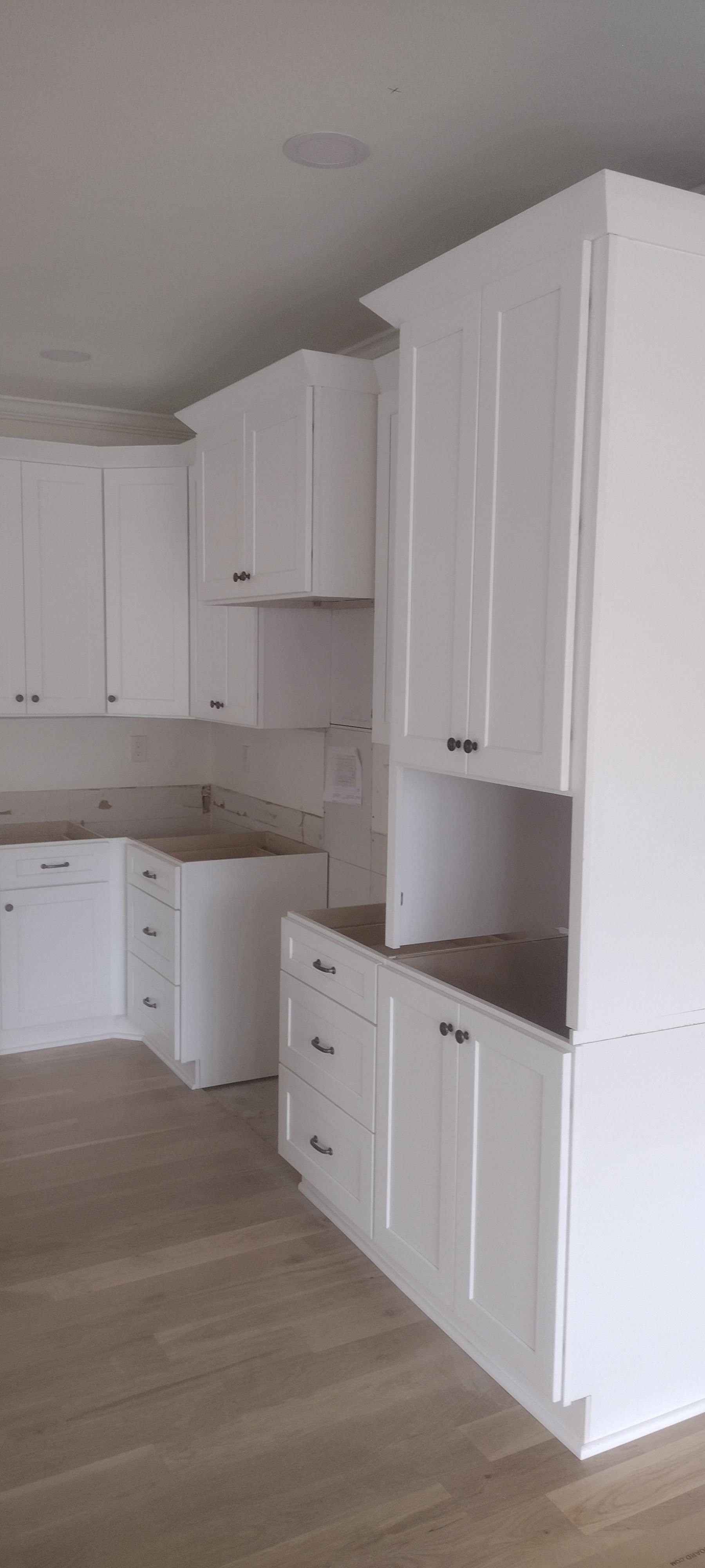 White kitchen cabinets in a new home, wood flooring.