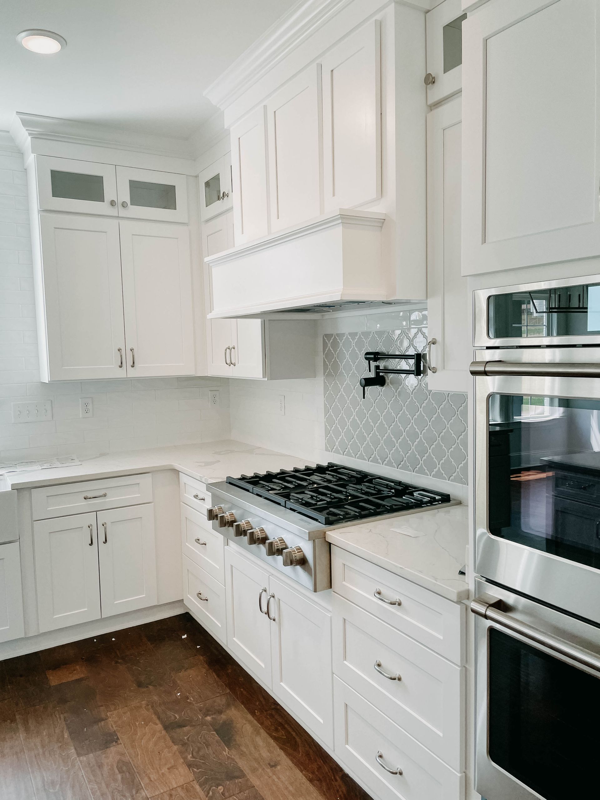 White kitchen with stainless steel appliances, white cabinets, and dark hardwood floors.