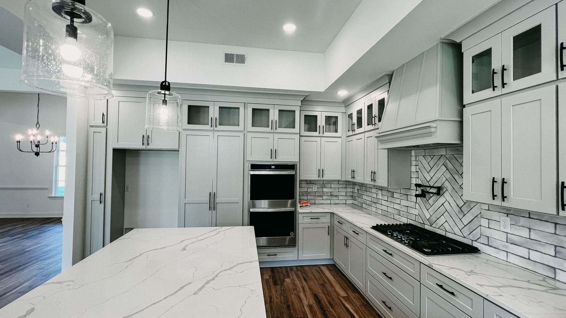 Modern kitchen with light gray cabinets, quartz countertops, and stainless steel appliances.