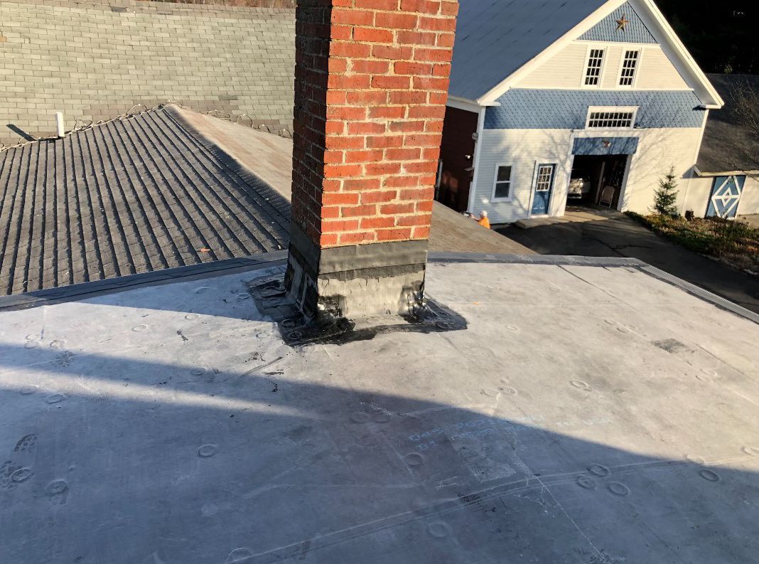 A brick chimney is on the roof of a house.