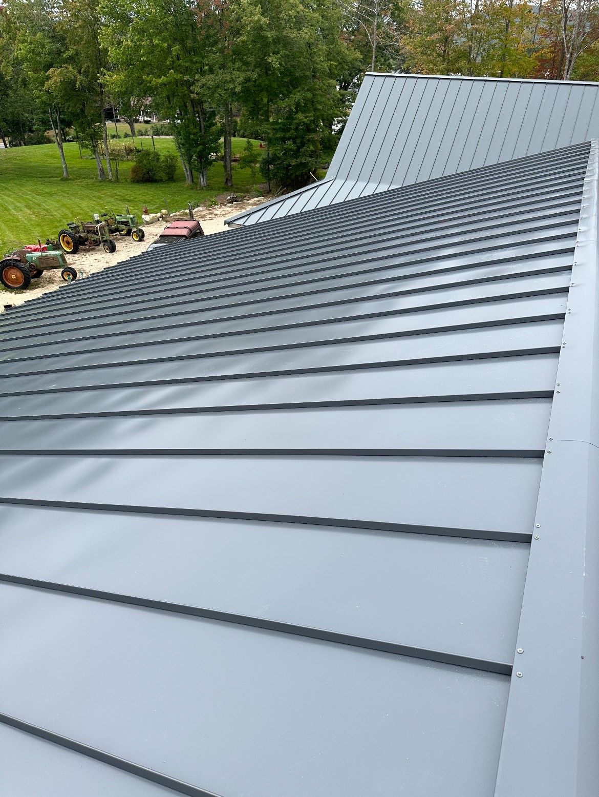 A close up of a metal roof with a tractor in the background.