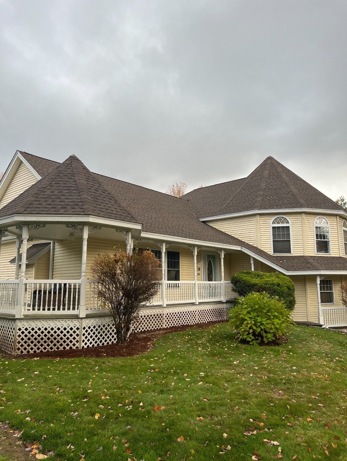 A large house with a large porch and a gray roof.