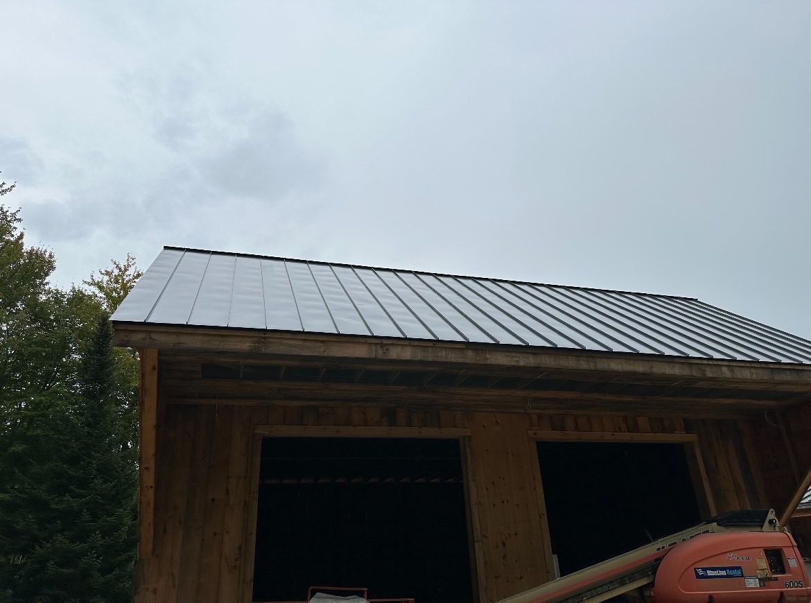 A metal roof is being installed on a wooden building.