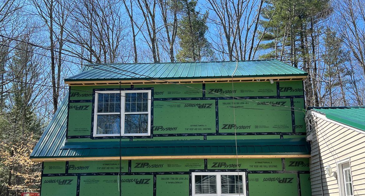 A house is being built with green siding and a green roof.