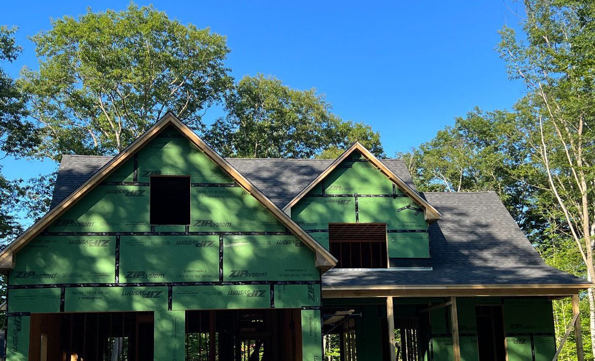 A house is being built with green siding and a black roof.