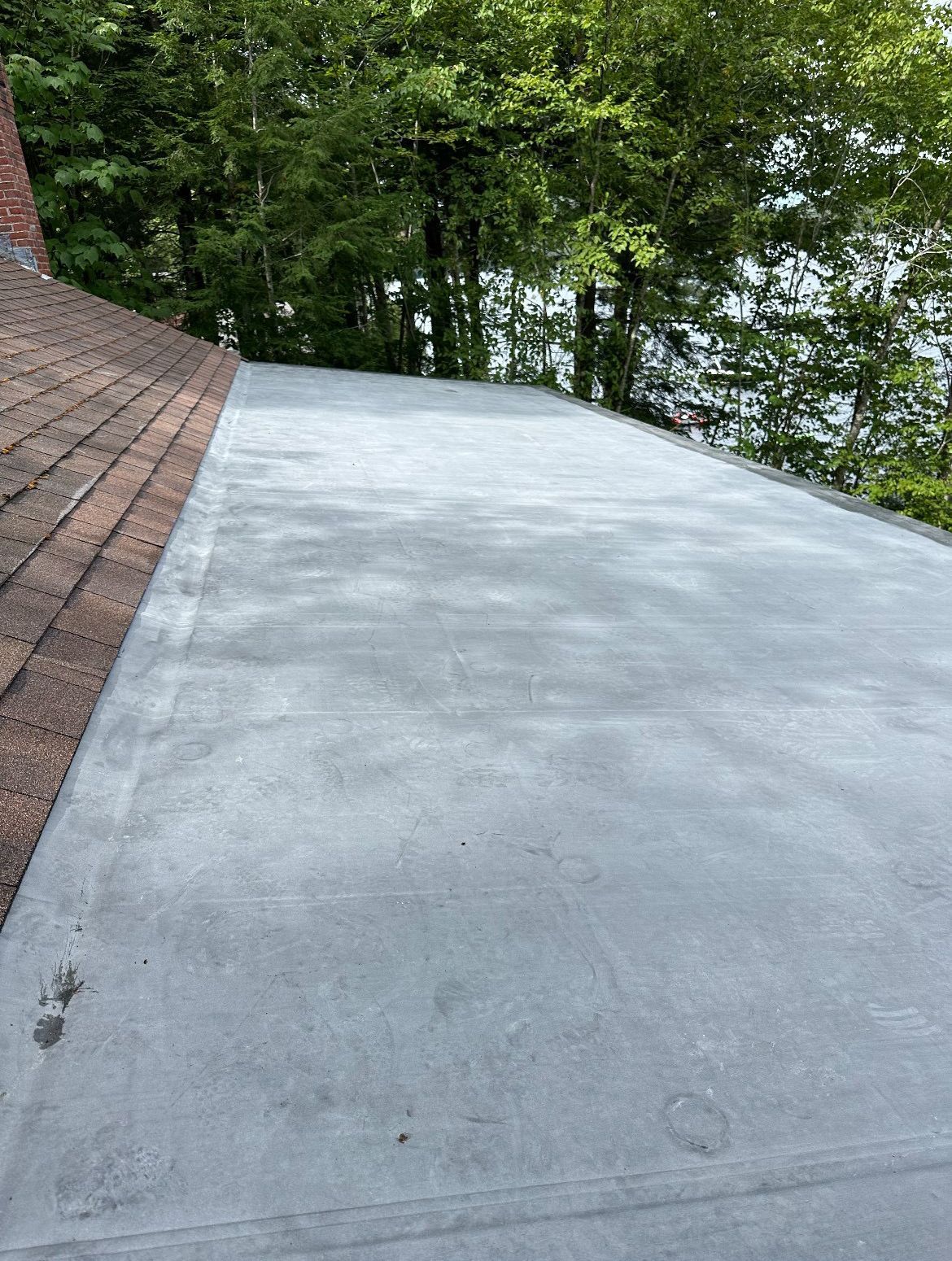 A concrete driveway with a roof and trees in the background.