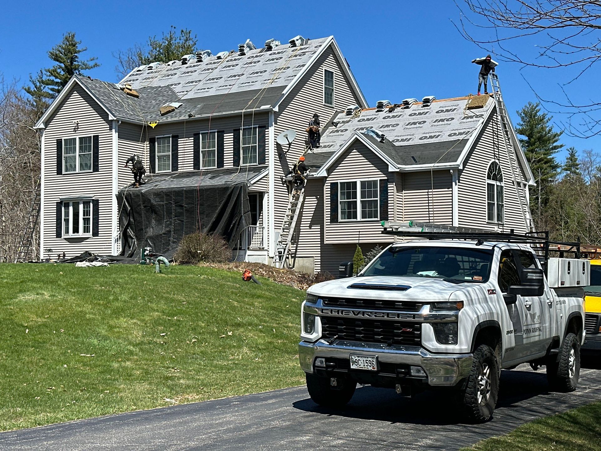 A white truck is parked in front of a large house.