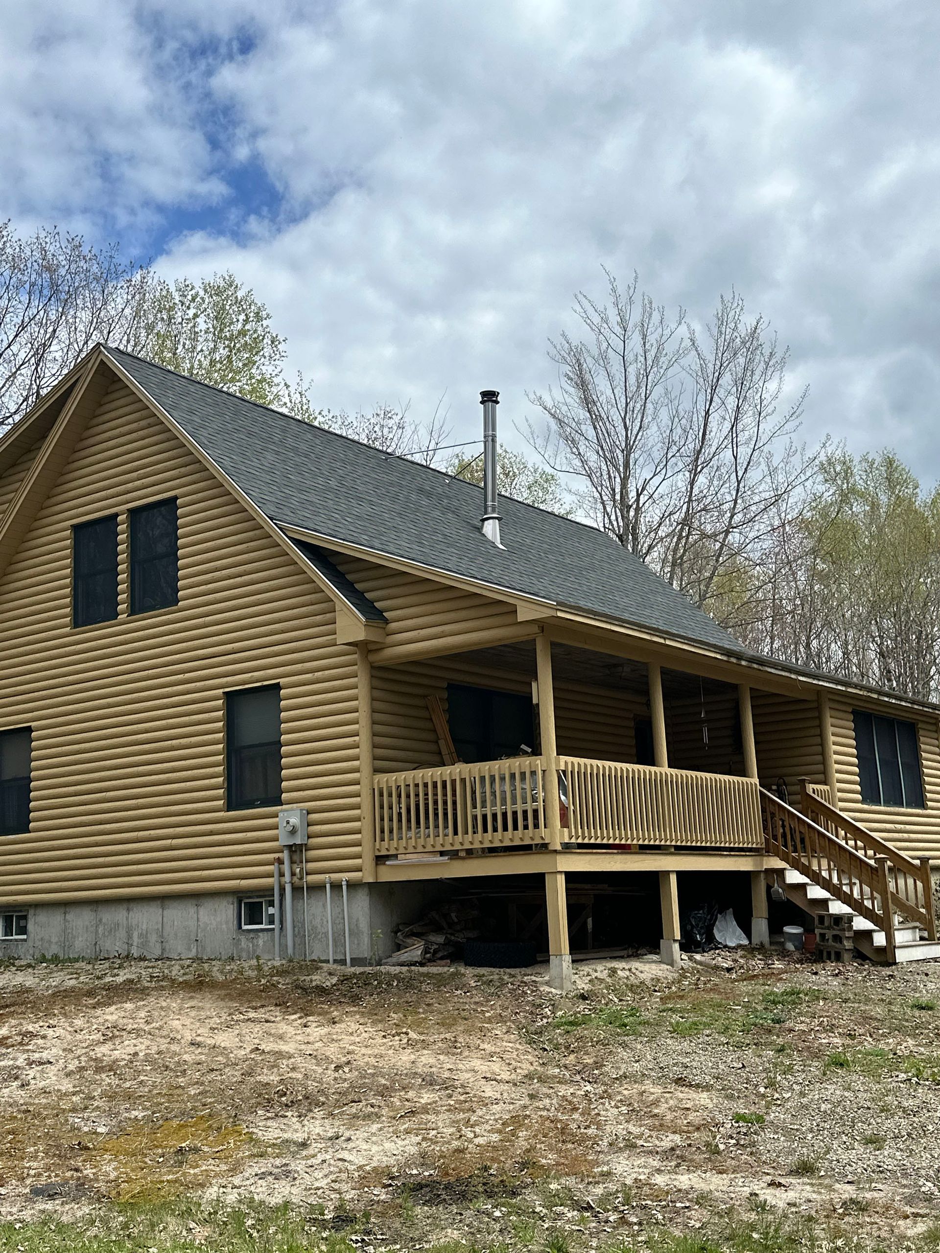 A large wooden house with a porch and stairs.