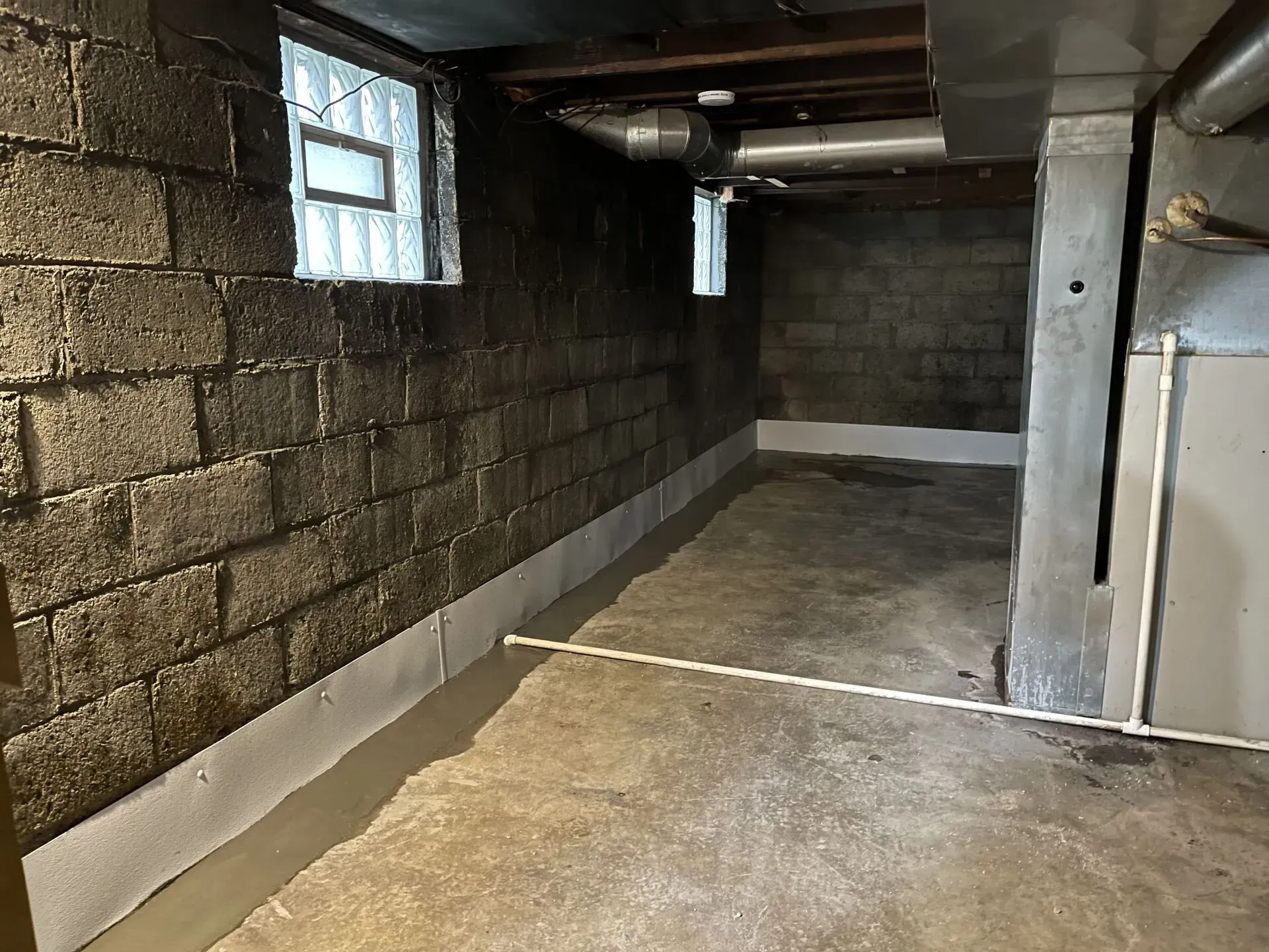 Empty basement with cinder block walls, concrete floor, and small windows.