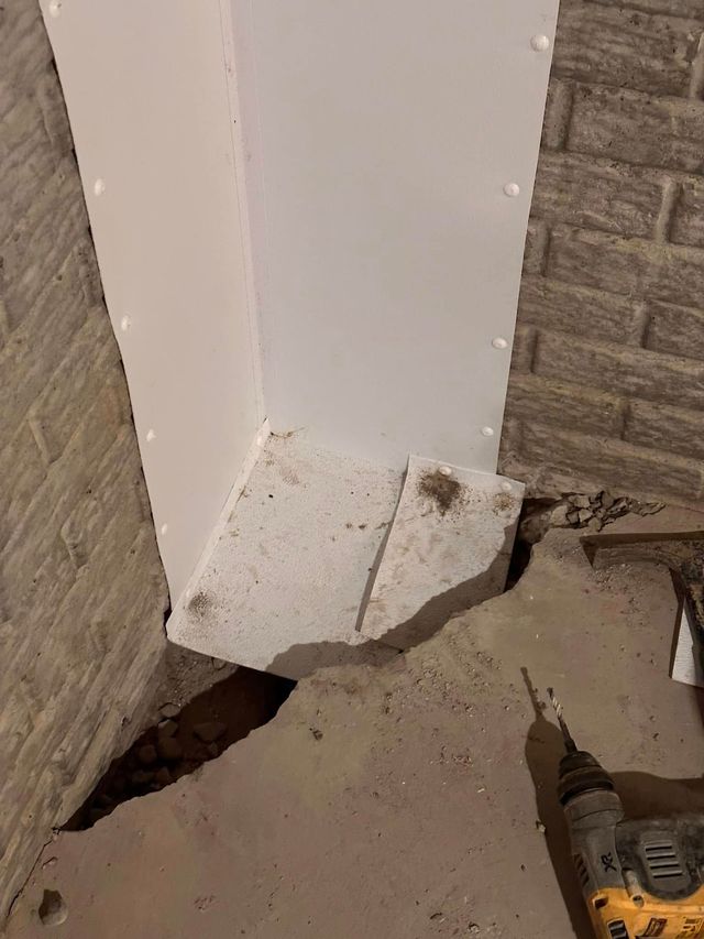 Damaged white corner trim on a building exterior, with broken concrete at the base and exposed gap underneath